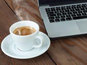 A house sitter communicating with her laptop and a cup of coffee.